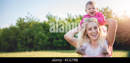 Mutter mit Baby Tochter Huckepack und stehen durch das Weizenfeld Stockfoto