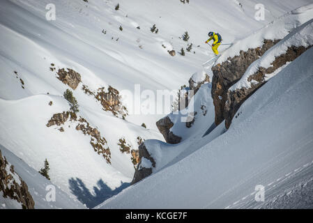 Ein Skifahrer springt vom Felsen beim Skifahren off piste im Französischen Courchevel. Stockfoto