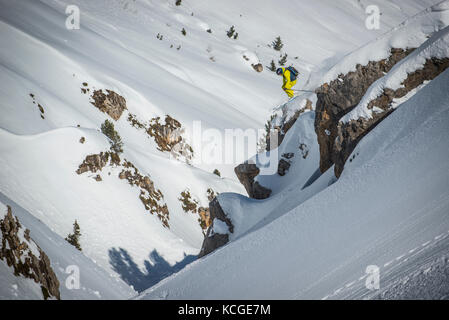 Ein Skifahrer springt vom Felsen beim Skifahren off piste im Französischen Courchevel. Stockfoto