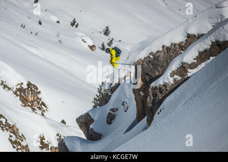 Ein Skifahrer springt vom Felsen beim Skifahren off piste im Französischen Courchevel. Stockfoto