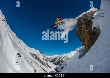 Ein Skifahrer springt vom Felsen beim Skifahren off piste im Französischen Courchevel. Stockfoto