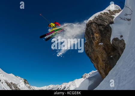 Ein Skifahrer springt vom Felsen beim Skifahren off piste im Französischen Courchevel. Stockfoto