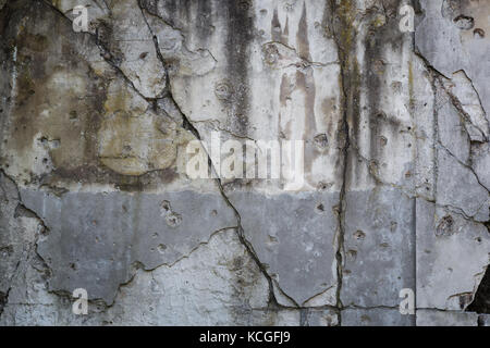 Alte, beschädigte und Risse in der Wand mit echten Einschusslöcher aus dem zweiten Weltkrieg in Danzig, Polen. Hintergrund Textur mit Vignettierung. Stockfoto