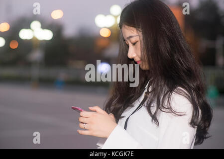Die junge Frau ein Handy nachts verwenden Stockfoto