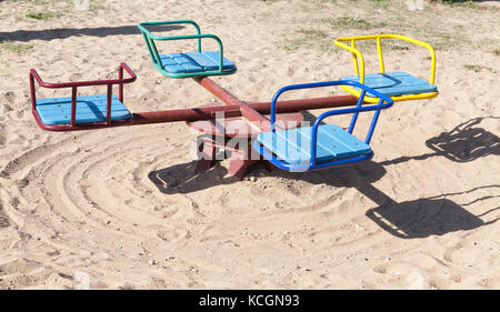 Die kleinen Kinder Karussell auf dem Spielplatz. Foto close-up. Licht Sand wurde auf den Boden gegossen. Karussell alte mit einigen Mängeln Stockfoto