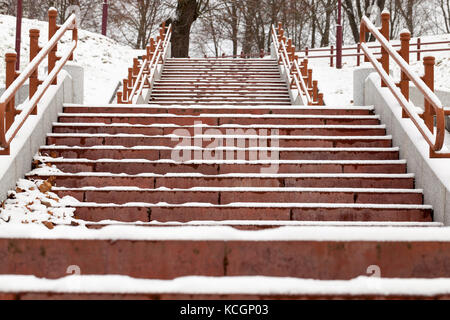 Verschneite Treppe im City Park. Die Treppe hat einen Handlauf. Schritte braun closeup von unten fotografiert. Stockfoto