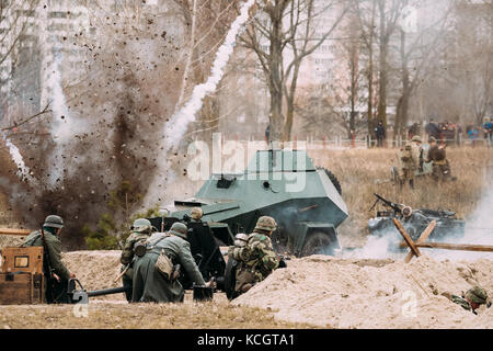 Als deutsche Soldaten verkleidete Reenactoren kämpfen im Zweiten Weltkrieg mit Einer Kanone auf das russische sowjetische Panzerauto während der historischen Nachstellung Stockfoto