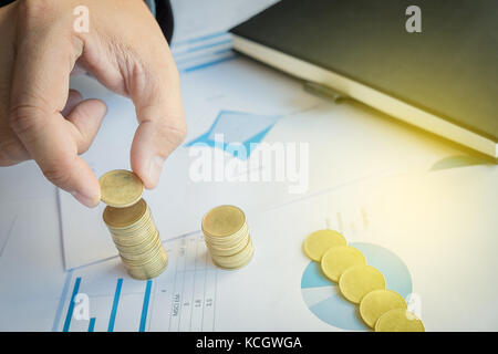 Nahaufnahme der Geschäftsmann Hand Münzen Münzen auf finanzielle Dokument zu Stapeln, Geschäftskonzept. Stockfoto