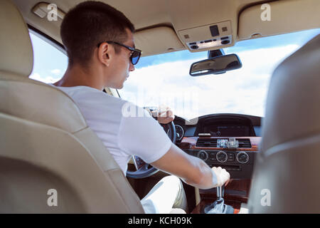 Junge stilvollen Mann in Sonnenbrille Autofahren. Blick von der Rückseite. Stockfoto