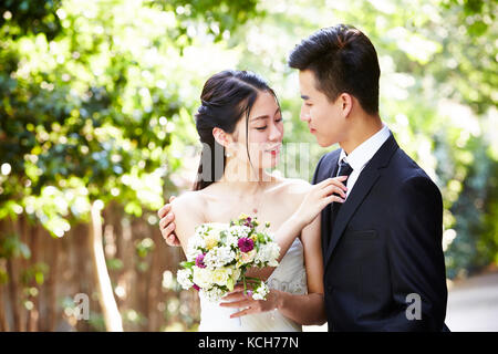 Jungen asiatischen Bräutigam Braut küssen im Freien während der Trauung. Stockfoto