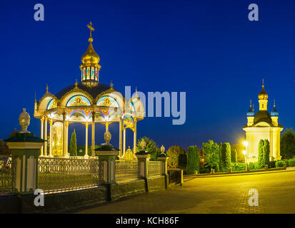 Wunderschöner Blick auf den Sommeraltar mit beleuchteter Dekoration in hellen Abendlichtern, Pochayiv Lavra Kloster, Ukraine Stockfoto