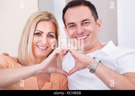 Portrait von glücklichen Mitte - erwachsene Paare bilden Herzform zusammen Stockfoto