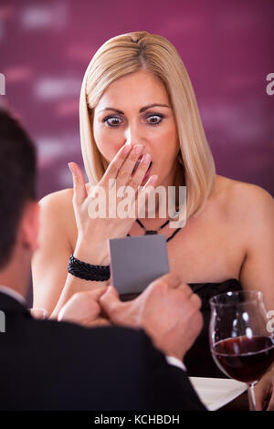 Überraschte Frau Beim Blick Auf Den Wedding Ring Im Restaurant Stockfoto