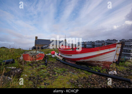 Ein paar der alten roten und weißen Boote Strände an der Küste durch den Hafen an der unteren milovaig, Isle of Skye, Schottland Stockfoto