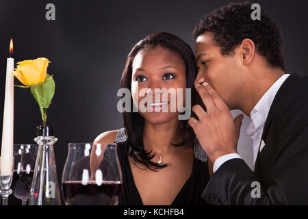 Porträt des Menschen Ohr flüstern zu der Freundin zum Abendessen Stockfoto