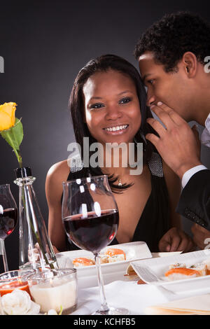 Porträt des Menschen Ohr flüstern zu der Freundin zum Abendessen Stockfoto