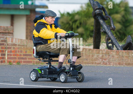 Älterer Mann reiten auf einem elektrisch angetriebenen Mobilität scooter, in Großbritannien. Stockfoto