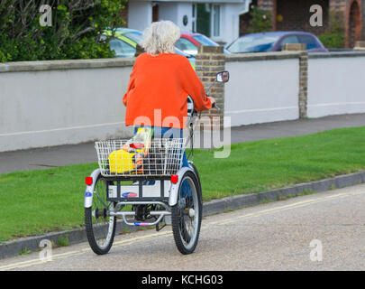 Ältere Frau Reiten eine Powabyke elektrisch angetriebenen Dreirad, auf der Straße in Großbritannien. Stockfoto