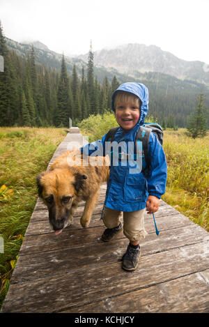 Ein glückliches Kind (junge) und seinem Hund Wanderungen auf der Promenade um Gibson See in Kokanee Glacier Provincial Park, British Columbia. Stockfoto