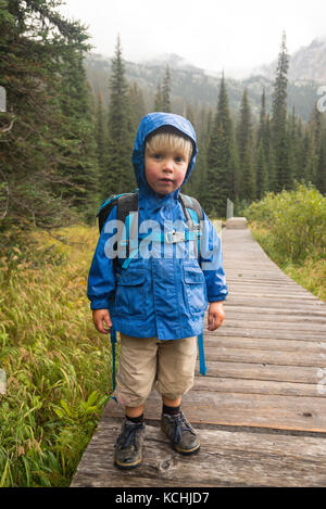 Ein Kleinkind (junge) stellt an einem regnerischen Promenade um Gibson See in Kokanee Glacier Provincial Park, British Columbia. Stockfoto