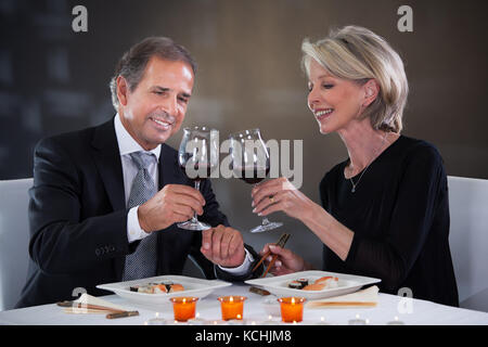 Gerne reifes Paar toasten Wein in einem eleganten Restaurant Stockfoto