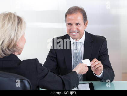 Gerne reife Geschäftsleute, die den Austausch von Visitenkarten im Büro Stockfoto