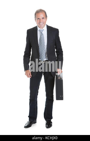 Porträt einer gut gekleidete Geschäftsmann stand mit verschränkten Armen Stockfoto