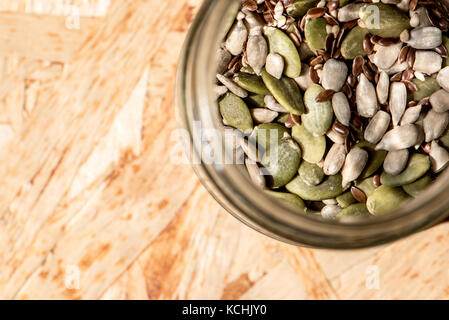 Mason jar voller Samen, gesunde Rohkost, Mix aus Flachs, Sesam, Kürbis- und Sonnenblumenkerne Stockfoto