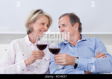 Portrait von Happy reifes Paar nebeneinander sitzen Testen mit Wein Stockfoto