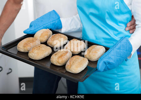 Mann sucht Frau unter Backblech heraus aus dem Ofen Stockfoto