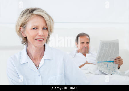 Glücklich Reife Frau sitzt vor Mann lesen Zeitung Stockfoto