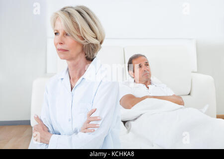 Traurig sitzt am Rand des Bettes vor Mann Frau Stockfoto