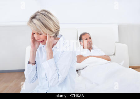 Traurig sitzt am Rand des Bettes vor Mann Frau Stockfoto