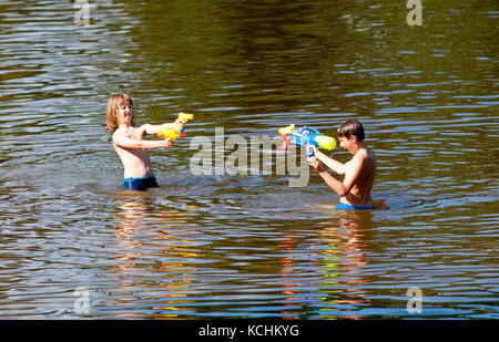Zwei Jungen kämpfen mit sprizen Gewehren in den See. Stockfoto