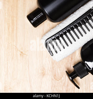 Haarpflege Hintergrund. Shampoo, Conditioner, breiten Zahn Kamm, weiße Frottee Handtuch auf Holz- Oberfläche. Kopieren Sie Platz Stockfoto