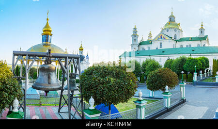 Der Panoramablick auf den Innenhof von Pochayiv Lavra mit Glocken im Freien und Dormition Cathedral im Hintergrund, Pochayiv, Ukraine Stockfoto