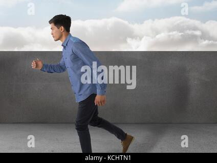 Digital composite der Geschäftsmann full body Geschäftsmann läuft durch Steinmauer und Wolken Stockfoto
