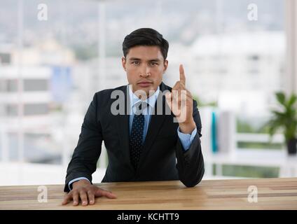 Digital composite der Geschäftsmann nach oben zeigen, während sitzt an seinem Schreibtisch im Büro Stockfoto
