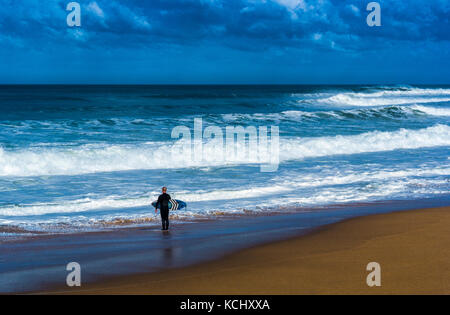 Der einsame Surfer am Strand ca. in die Brandung zu paddeln Stockfoto