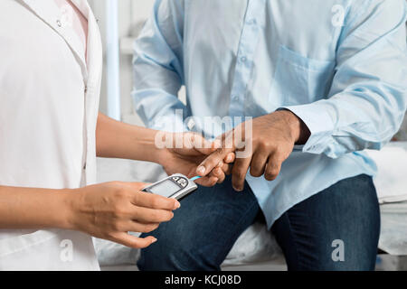 Frau Doktor, Prüfung der Blutzuckerspiegel des Patienten mit glucometer Stockfoto