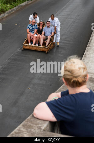 Sie Touristen hinunter die Straße in wicker Schlitten in Monte in der Nähe von Funchal auf Madeira schieben Stockfoto