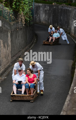 Touristen schieben den Hügel hinunter in traditiopnal Weidenkorb Schlitten in Monte in der Nähe von Funchal auf Madeira Stockfoto