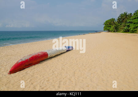 Bunte dugout Fischerboot Verlegung auf einsamen tropischen Strand bei robertsport, Liberia, Westafrika Stockfoto