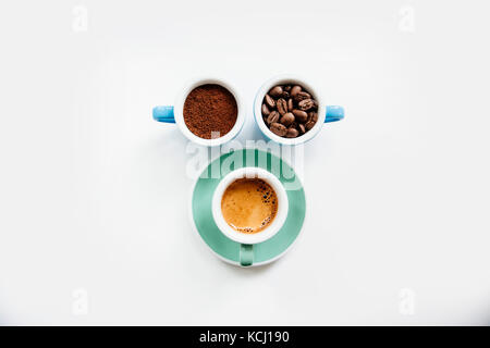 Drei Tassen Kaffee: Kaffee (Pulver), Kaffeebohnen und frisch zubereiteten Espresso in farbenfrohe Keramik Tassen (mint grün und hellblau) auf dem Weißen Stockfoto