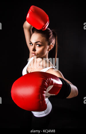 Schöne junge Frau in einem roten Boxhandschuhe über schwarzen Hintergrund (der Fokus liegt auf dem Handschuh) Stockfoto