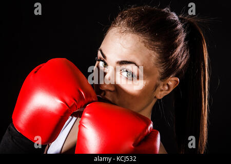 Schöne junge Frau in einem roten Boxhandschuhen auf schwarzem Hintergrund Stockfoto