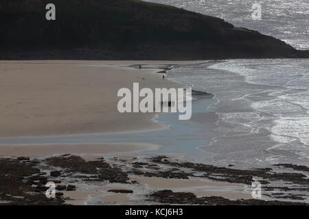 Dunraven Bay in der Nähe des Dorfes Southerndown mit der Tide Recht, und eine Gruppe von Personen standen auf der Tide line und Hund Wanderer. Stockfoto