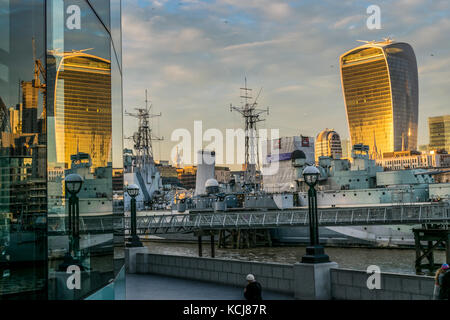 Golden Sunset Reflexion walkie talkie Gebäude im modernen verglasten Gebäude an der South Bank in London mit der HMS Belfast wiederholt Stockfoto