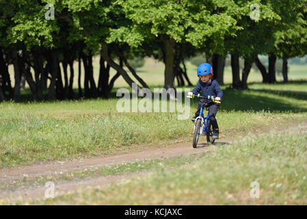 Glückliches Kind Junge von 5 Jahren Spaß im Frühjahr Wald mit dem Fahrrad auf schönen Herbst Tag. aktives Kind Fahrrad Helm tragen. Stockfoto