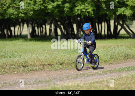 Glückliches Kind Junge von 5 Jahren Spaß im Frühjahr Wald mit dem Fahrrad auf schönen Herbst Tag. aktives Kind Fahrrad Helm tragen. Stockfoto